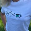 The woman wears the white T-shirt and shows how it looks closer.